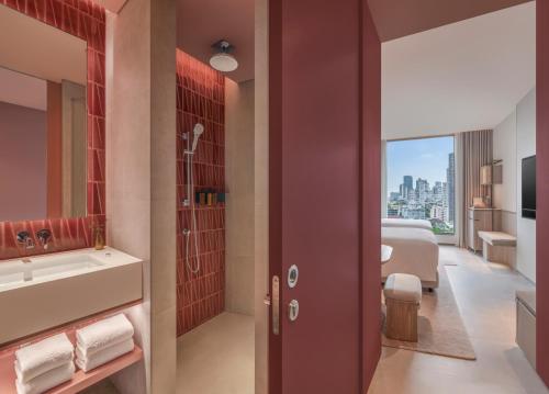a bathroom with a shower and a sink and a tub at Kromo Bangkok, Curio Collection By Hilton in Bangkok
