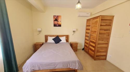 Un dormitorio con una cama y un armario de madera. en Le Mirage Exotique, en Flic en Flac