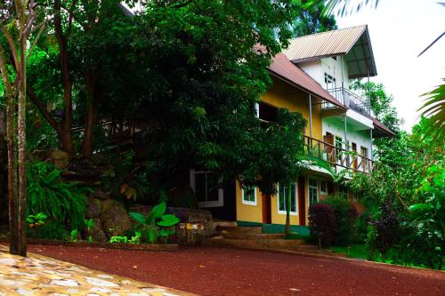 a yellow and white house with a tree at Skill forest lodge in Arusha