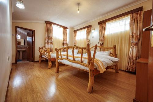 a bedroom with a wooden bed and wooden floors and windows at Solio Gardens Nanyuki in Nanyuki