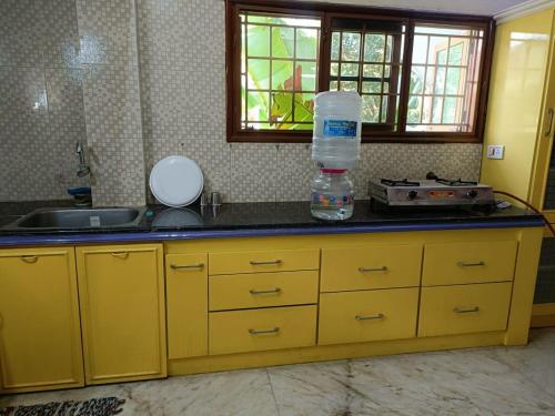 a kitchen with yellow cabinets and a sink and a counter top at Thuyil Home Stay in Tirunelveli