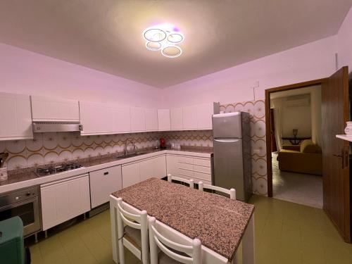 a kitchen with white cabinets and a table and a refrigerator at Casa Lauretta in Campofelice di Roccella