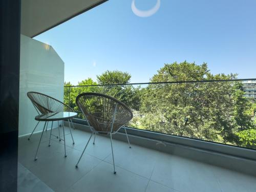 a balcony with two chairs and a view of trees at VILLA 8 By ProLiving Hospitality in Thessaloniki