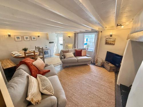 a living room with two couches and a table at Luxury Cornish Cottage & Modern Cabin with Garden, Central St Agnes in St. Agnes