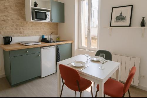 une petite cuisine avec une table et des chaises blanches dans l'établissement Appartement Cosy Hypercentre CAEN, à Caen
