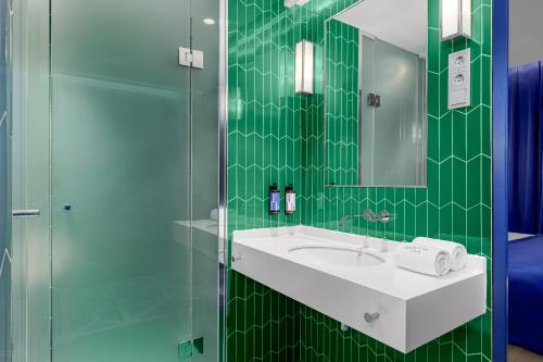 a green tiled bathroom with a sink and a shower at Room Mate Macarena, Madrid Gran Vía in Madrid