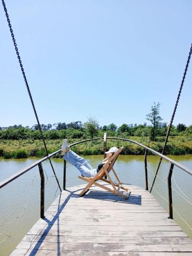 a person laying in a chair on a bridge over water at Iveria Parky and cottages in Shekvetili