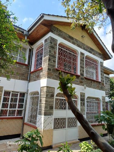 a house with red windows and a tree at BERNKISH HOMES in Nakuru