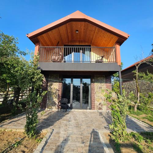 a house with a balcony on top of it at Iveria Parky and cottages in Shekvetili