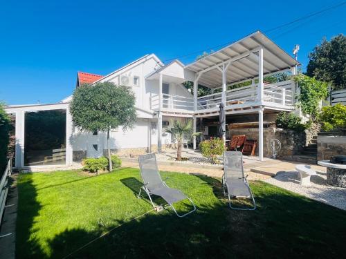 a house with two lawn chairs in the yard at Bálics Vendégház in Pécs