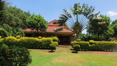 a house with green bushes in front of a yard at Solio Gardens Nanyuki in Nanyuki