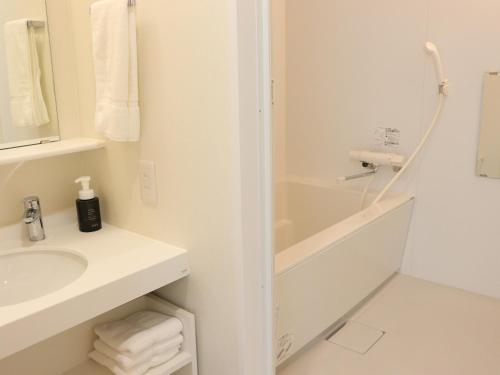 a white bathroom with a sink and a shower at Shin-Osaka Station Hotel in Osaka