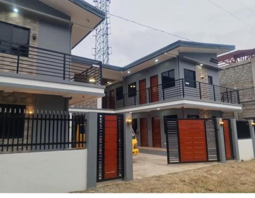 a large house with red doors and a balcony at Cozy Apartment near Dahican beach in Dahikan