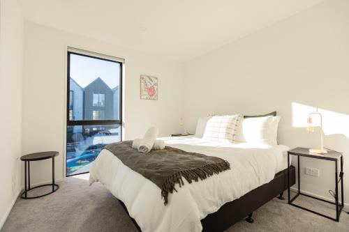 een slaapkamer met een groot bed en een groot raam bij Luxury CBD 2Bed2Bath With Parking Near Parks in Christchurch