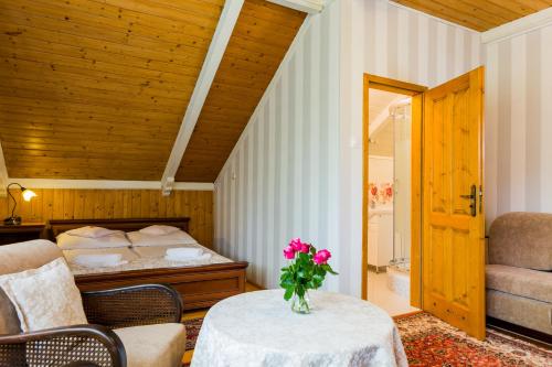 a room with a bed and a table with a vase of flowers at Villa Cynamon Jacuzzi & Sauna in Wisła