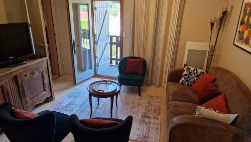 a living room with a couch and chairs and a television at Le Domaine de la Répandise in Laveline-du-Houx