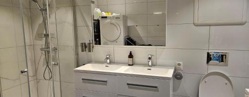 Un baño blanco con lavabo y ducha. en Lakeside apartment, en Stryn
