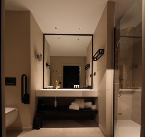 a bathroom with a sink and a shower and a mirror at Hotel Sanglier in Durbuy