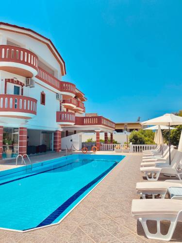 a hotel with a swimming pool and lounge chairs at Hotel Alexandros in Ammoudia