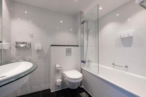 a white bathroom with a toilet and a sink at Copenhagen Island Hotel in Copenhagen