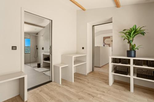 La salle de bains est pourvue de murs blancs et d'un grand miroir. dans l'établissement Domaine du verneton, à Les Brugassières