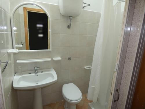 a bathroom with a sink and a toilet and a mirror at Cardiff Hotel in Marina di Camerota
