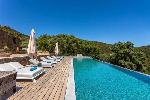 - une piscine avec chaises longues et parasols sur une terrasse en bois dans l'établissement Domaine du verneton, à Les Brugassières