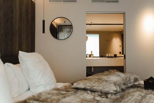 a bedroom with a bed with a mirror on the wall at Hotel Sanglier in Durbuy