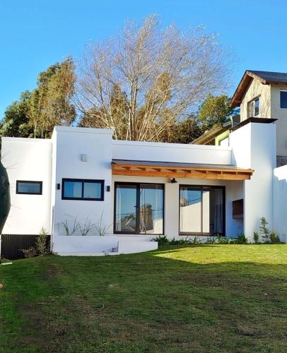 a white house with a green yard at Cabaña Matorras 480 in Tandil