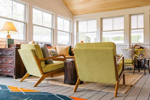 a living room with chairs and a table and windows at Camp DeForest in Lincolnville