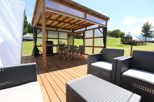 a wooden deck with wicker chairs and a gazebo at 舞子グランピング in Minami Uonuma