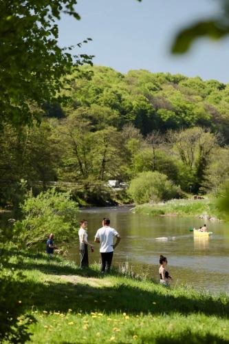 a group of people standing in the water near a river at Camping Le Florenville in Florenville