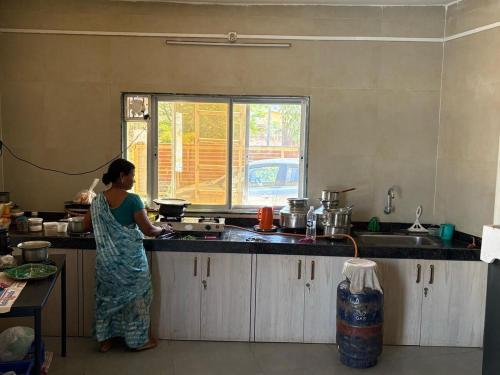 a woman standing in a kitchen preparing food at Pali Retreat Riverside Stay with Pool in Pali