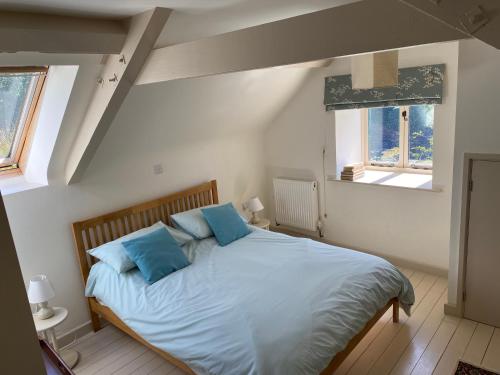 a bedroom with a large bed with blue pillows at Little Llanvolda in Saint Maughans