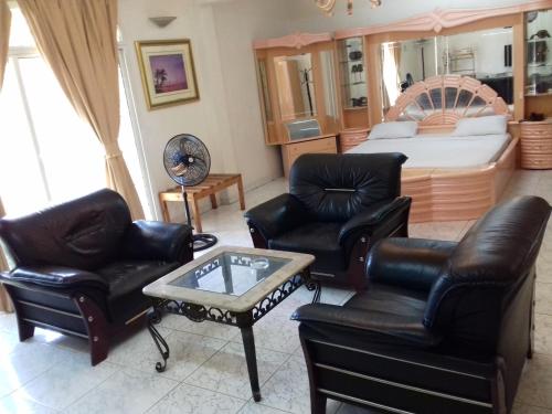 a living room with leather furniture and a bed at Sophia Hotel in Dar es Salaam