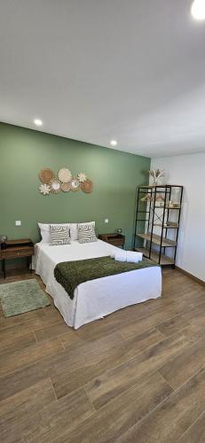 a bedroom with a large bed and a green wall at Casa das Boucinhas in São Sebastião de Penha Longa