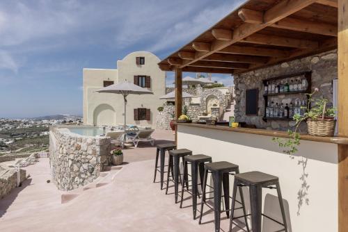 a bar on the roof of a house with stools at Zatrikion Santorini Villas in Pirgos