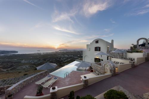 a villa with a view of the ocean at sunset at Zatrikion Santorini Villas in Pirgos