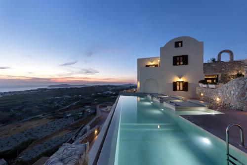 a villa with a swimming pool at night at Zatrikion Santorini Villas in Pirgos