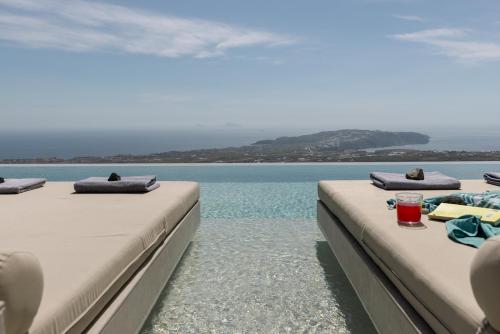 two beds on a pool with the ocean in the background at Zatrikion Santorini Villas in Pirgos