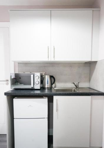 a kitchen counter with a microwave and a sink at Ryegate House Colchester in Colchester