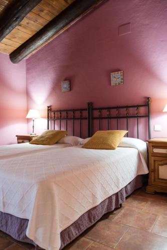 a bedroom with a large bed with a purple wall at Hotel Albarrán in Albarracín