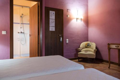 a bedroom with a bed and a chair and a window at Hotel Albarrán in Albarracín