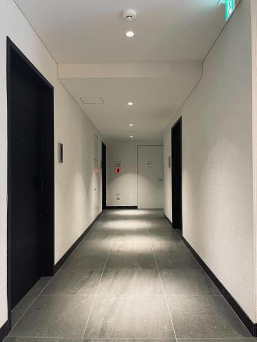 an empty hallway with white walls and black doors at Alo BnB 11 - Near Roppongi, Ginza, Shinjuku, Shibuya - Self check-in in Tokyo
