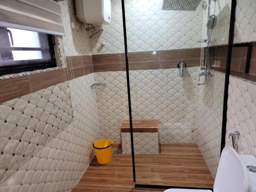a bathroom with a shower with a yellow trash can at Caesar's Hotel & Apartment Room 6 in Ikeja