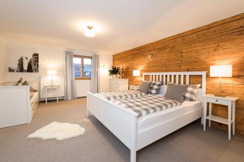 um quarto com uma cama branca e uma parede de madeira em "Viktoria Ferienhaus" - Annehmlichkeiten von 4-Sterne Familien-und Wellnesshotel Viktoria können mitbenutzt werden em Oberstdorf