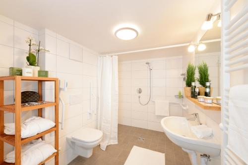ein weißes Bad mit einem WC und einem Waschbecken in der Unterkunft "Viktoria Ferienhaus" - Annehmlichkeiten von 4-Sterne Familien-und Wellnesshotel Viktoria können mitbenutzt werden in Oberstdorf