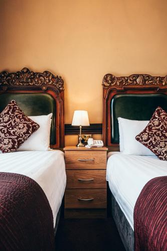 a hotel room with two beds and a table with a lamp at Russell Court Hotel in Dublin