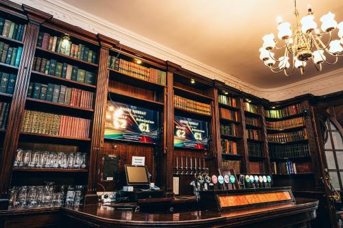 a library with book shelves filled with books at Russell Court Hotel in Dublin