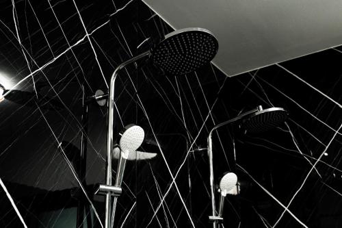 two shower heads in a bathroom with black tiles at Casa Bianca in Barbat na Rabu